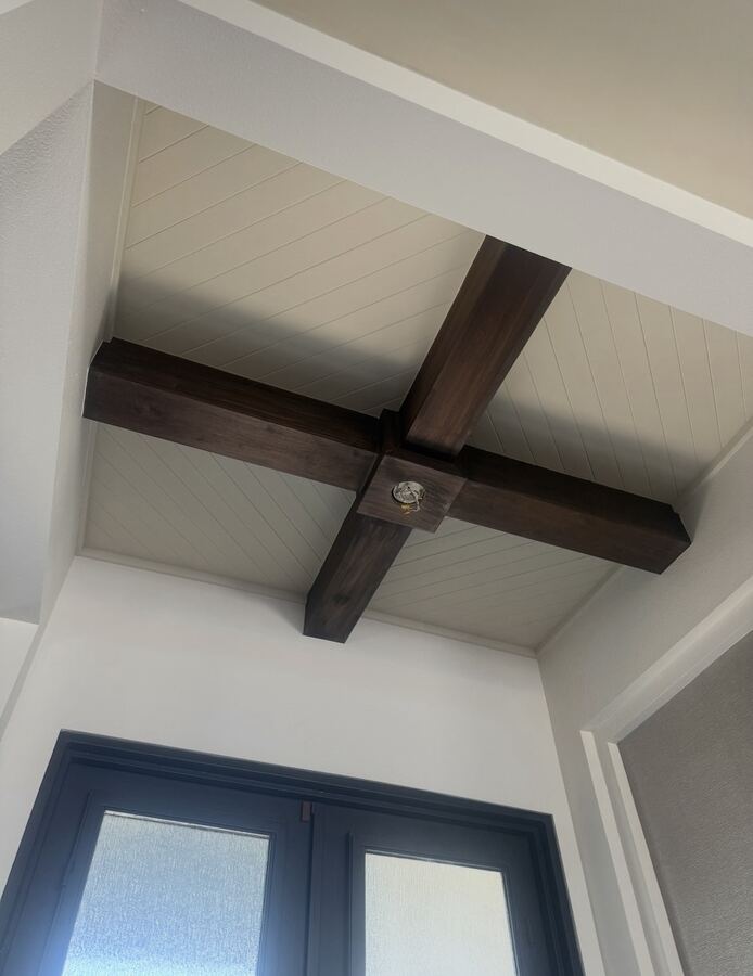 Dark-stained wood ceiling beams over navy French doors