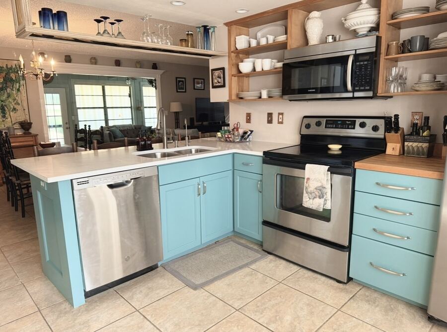 Kitchen cabinets refinished in light teal with stainless appliances