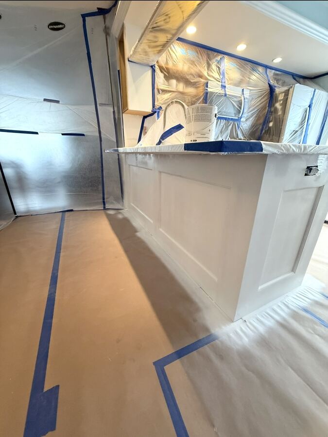 Kitchen island masked with plastic and floor paper before cabinet spraying