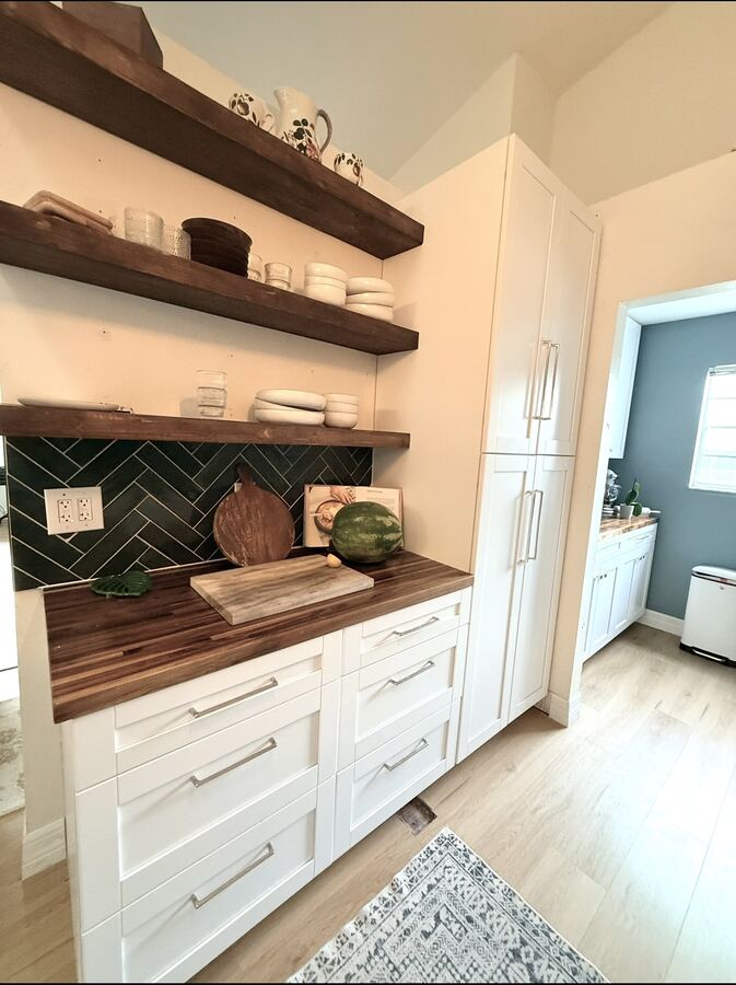 White butler's pantry cabinets with walnut shelves and green herringbone backsplash