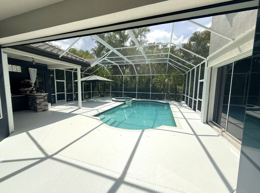 White-coated pool deck inside a screened lanai