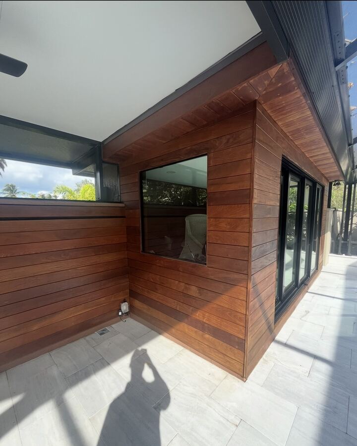 Finished wood-slat exterior wall with picture window and tile deck
