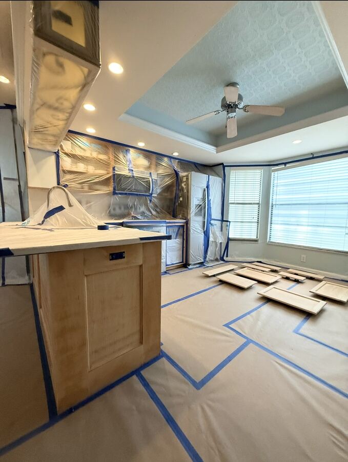 Kitchen masked for cabinet refinishing with doors laid out to spray