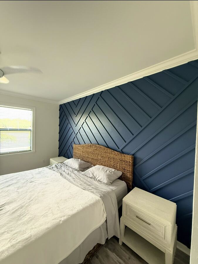 Navy geometric wood accent wall behind a bed