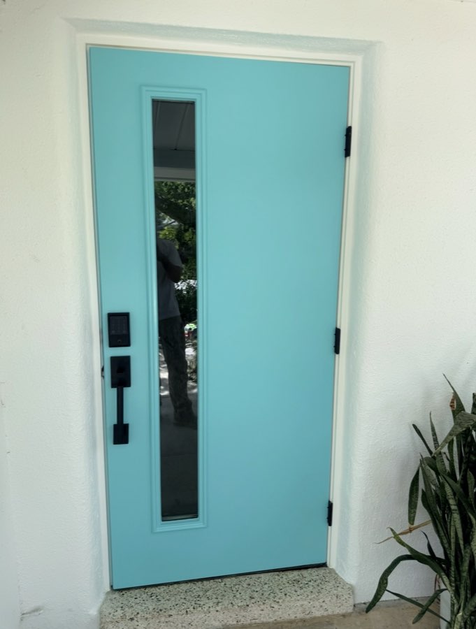 Freshly painted turquoise front door with black hardware and glass panel
