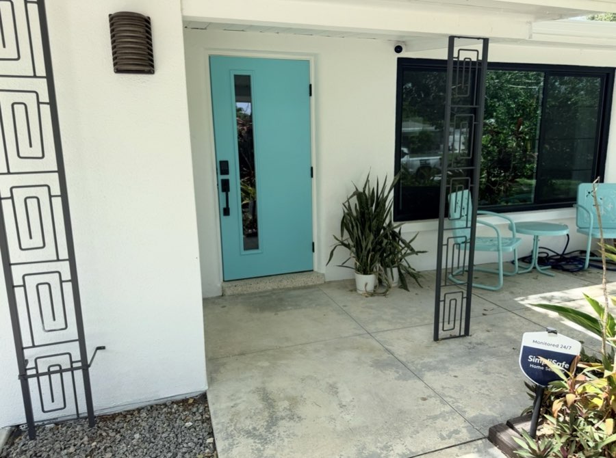 Turquoise front door and breezeblock privacy screen on a repainted patio entry