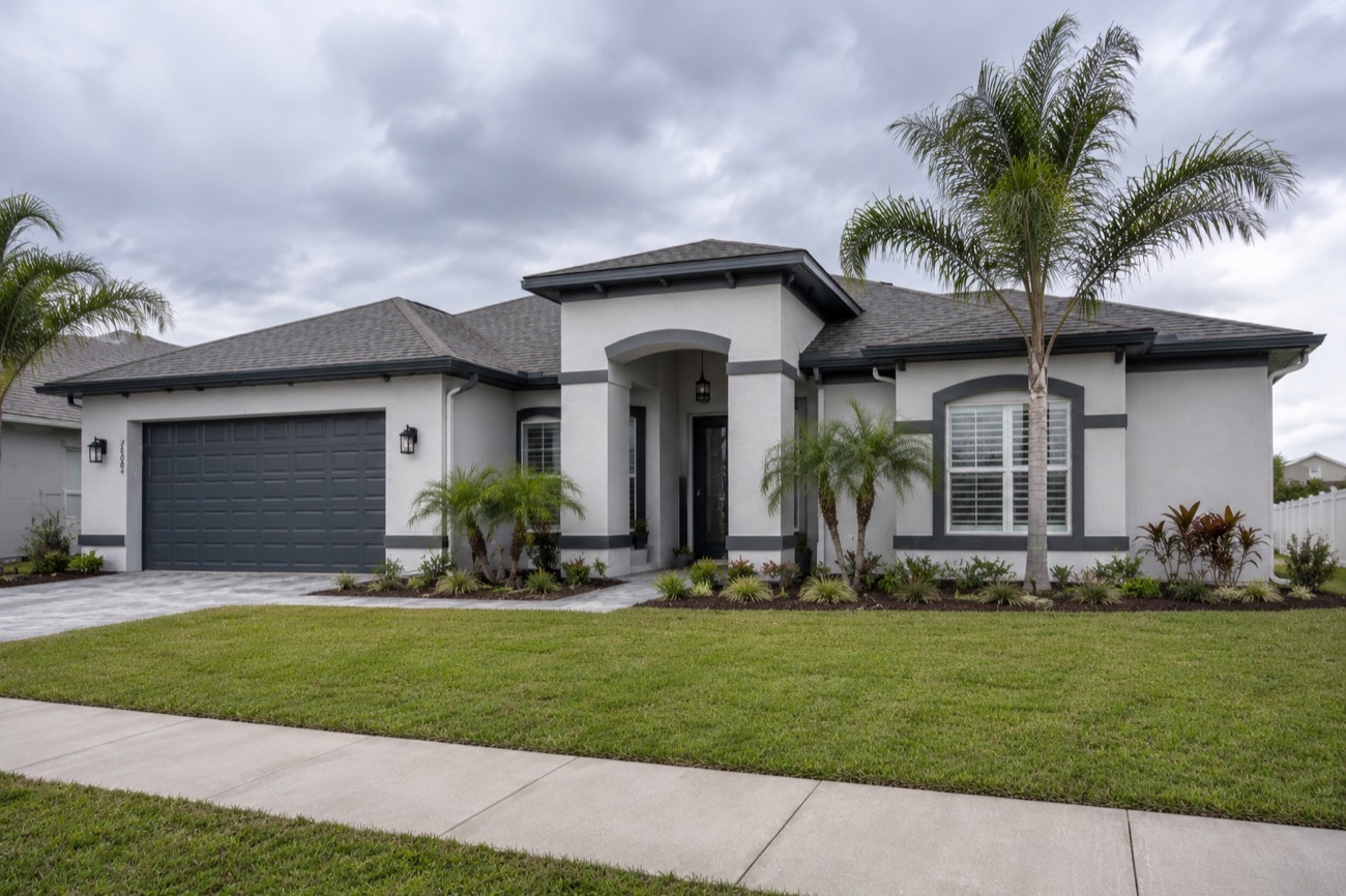 Florida home exterior with fresh white paint, dark garage door, and palm tree