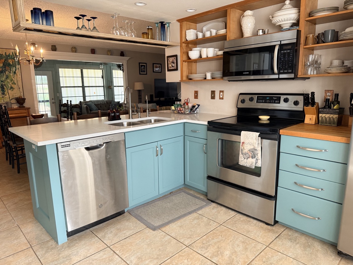 Kitchen after cabinet refinishing in light teal with stainless appliances