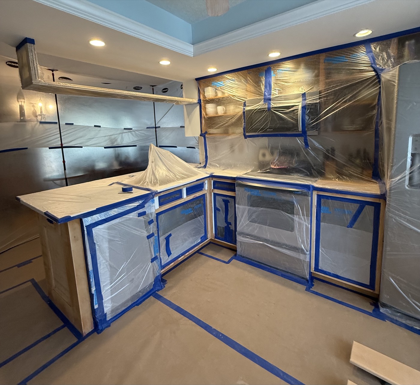 Same kitchen masked and prepped before cabinet refinishing