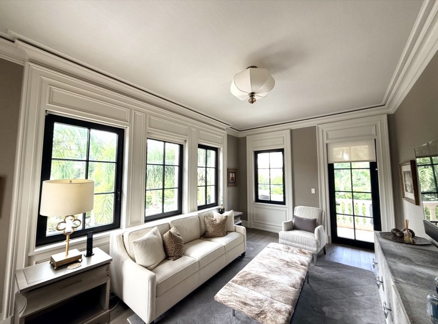Living room with painted wainscoting, black-framed windows, and coffered ceiling trim
