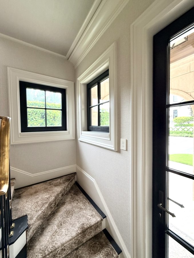 Painted stairwell landing with wainscoting and black-framed windows