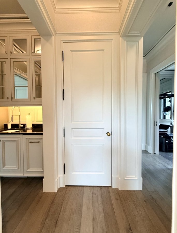 White paneled door with brass knob leading to a butler's pantry