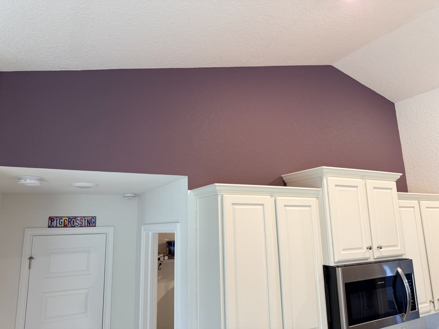 Painted mauve kitchen accent wall above white cabinets